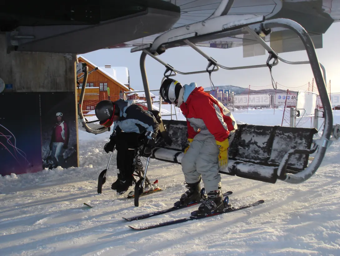 Standing and sitting alpinist getting into the chairlift