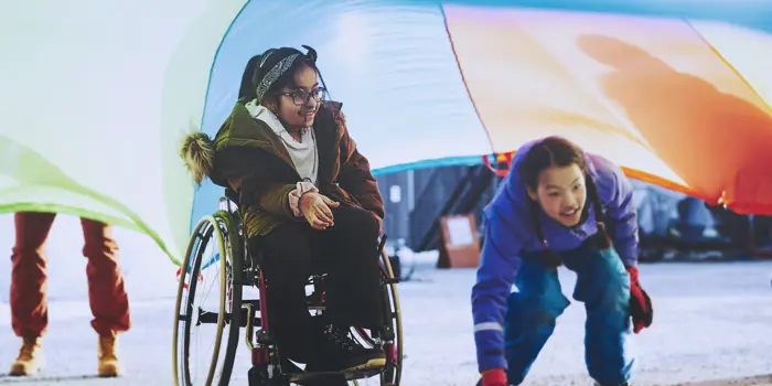 Two girls under a colorful parachute. Photo: Christine Stokkebryn