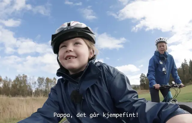 Skjermbilde fra filmen om barne- og ungdomstilbudet ved Beitostølen Helsesportsenter. En jente sykler foran instruktør. 