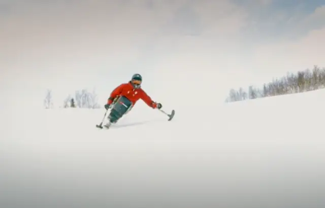 Alpinist i sit-ski i full fart ned alpinbakken