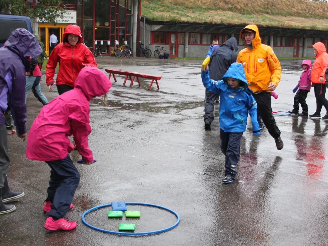 En gruppe barn og voksne har erteposestafett ute i regnet